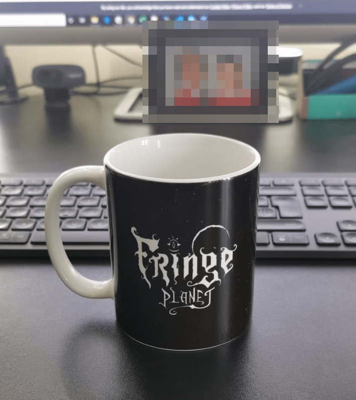 A Fringe Planet mug sitting on a desk